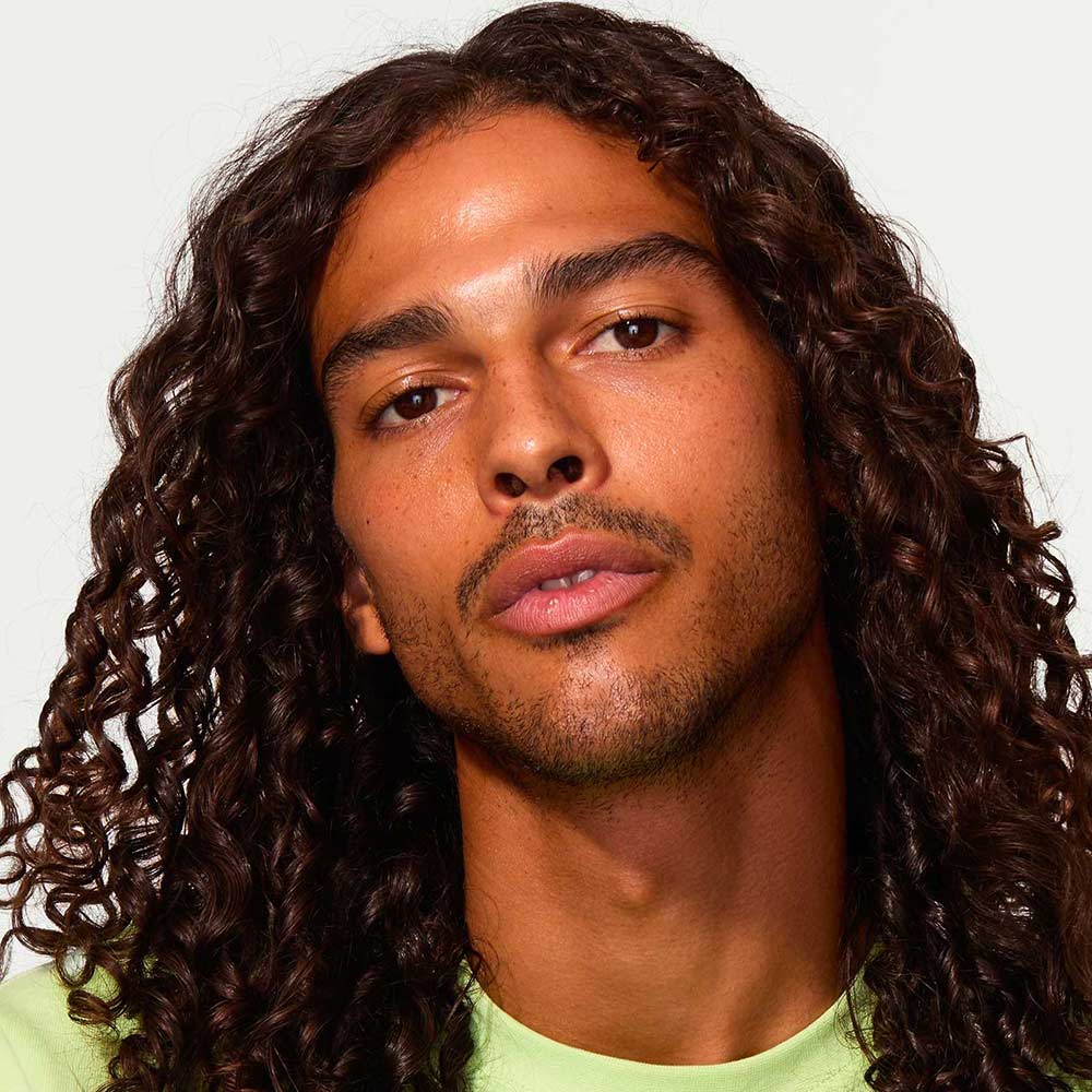 Male model with long curly hair looking straight forward